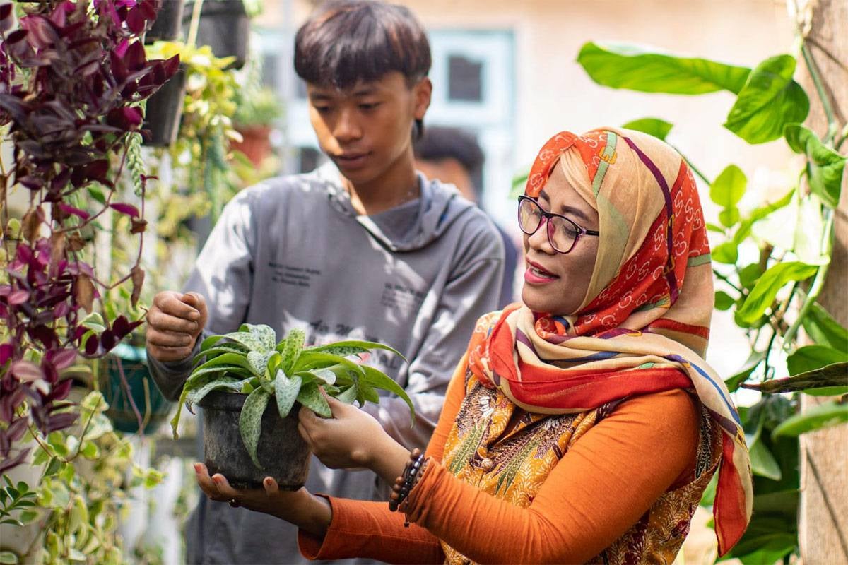 A teacher works with a student in the garden