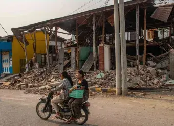 On 31 March 2025, two women are seen riding a motorcycle, passing by a collapsed building in Sagaing, Myanmar, following the 7.7-magnitude earthquake that struck Mandalay on 28 March. Photo: UNICEF/UNI771892/Htet